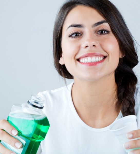 Smiling woman using mouthwash to maintain a clean smile