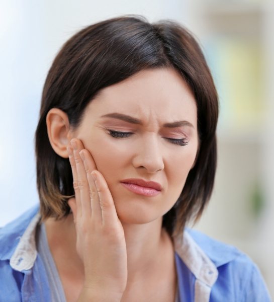Woman in need of dental checkup and teeth cleaning holding cheek in pain