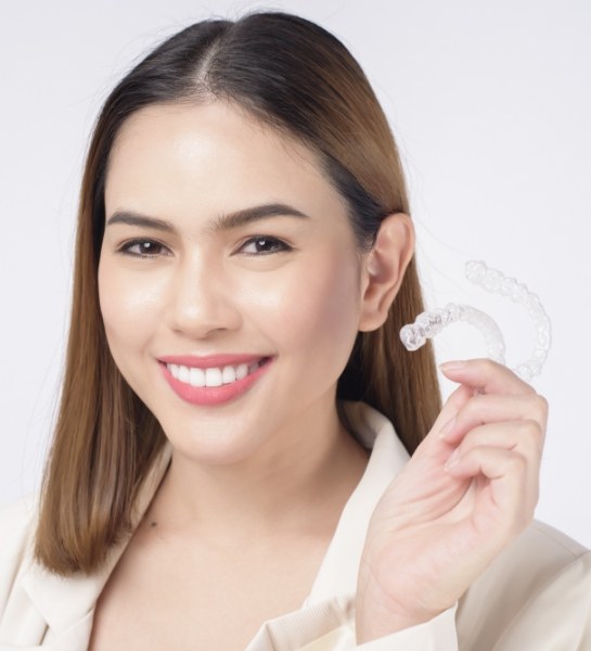 Woman holding up Invisalign clear aligners