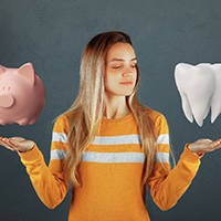 Woman with model of tooth in one hand and piggy bank in the other