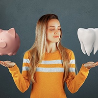 Woman with model of tooth in one hand and piggy bank in the other