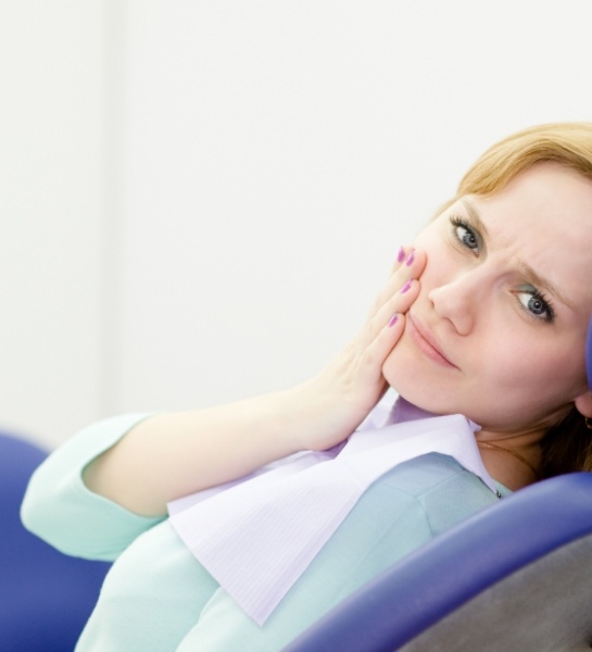Woman in need of tooth extraction holding cheek in pain