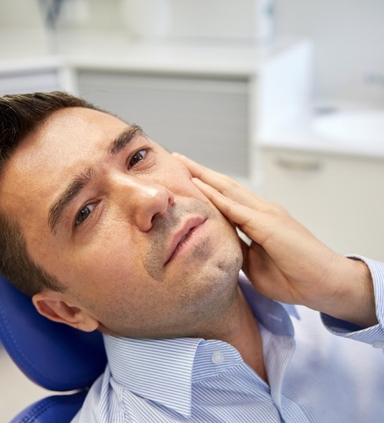 Man in need of tooth extraction holding cheek
