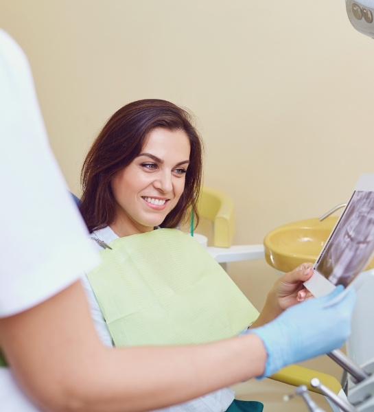 Woman looking at smile after tooth colored filling restoration