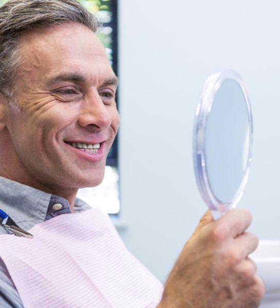 Man looking at smile after tooth colored filling restoration