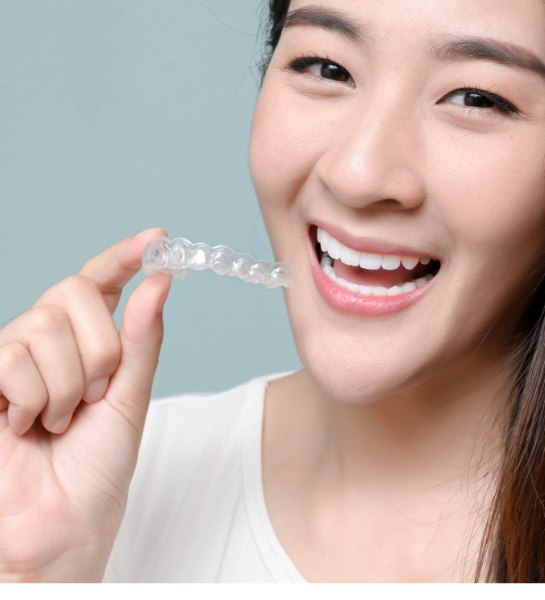 Smiling woman holding an Invisalign tray