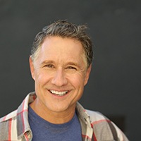 Man smiling in front of a chalkboard