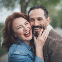 Man and woman enjoying the benefits of their investment in dental implants