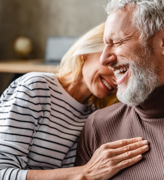 Man and woman smiling after tooth replacement with dental implants