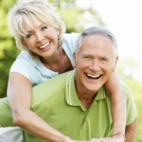 Older man and woman smiling after tooth replacement with dental implants