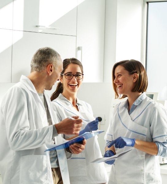 Dentist and dental team member reviewing the cost of dental implants