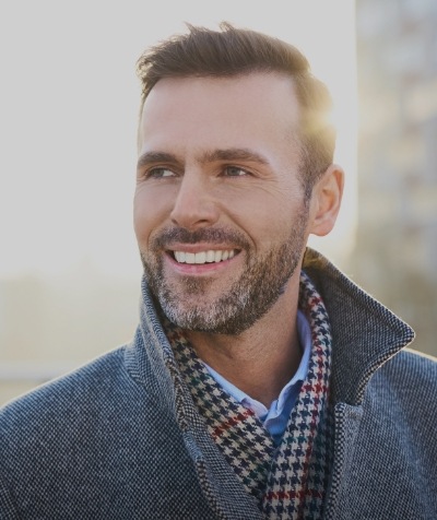 Man with plaid scarf smiling outdoors