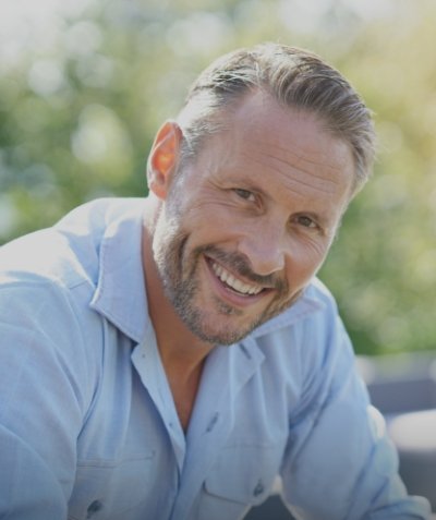 Man in light blue shirt smiling outdoors