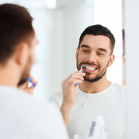 Man smiling while brushing his teeth