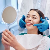 Patient smiling at reflection in handheld mirror