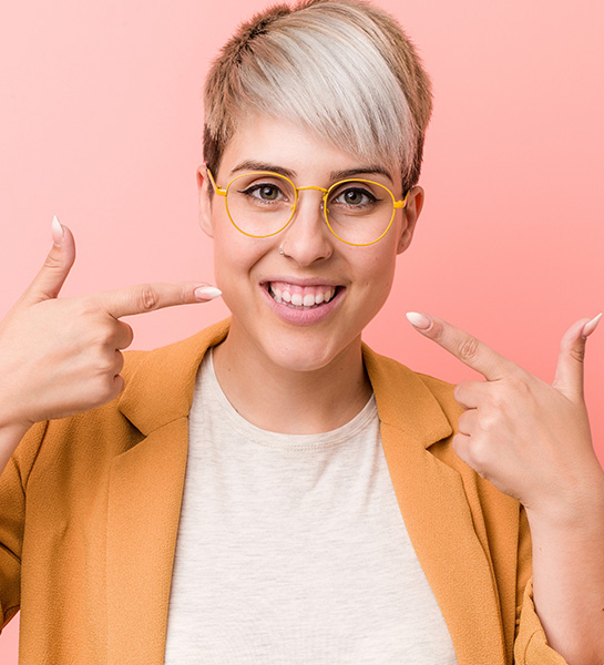 Dental patient pointing to smile after KoR teeth whitening