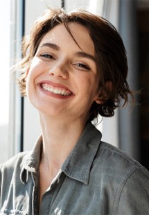 Close-up of woman standing next to window and smiling
