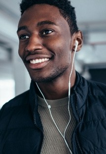 Smiling man listening to music with earbuds