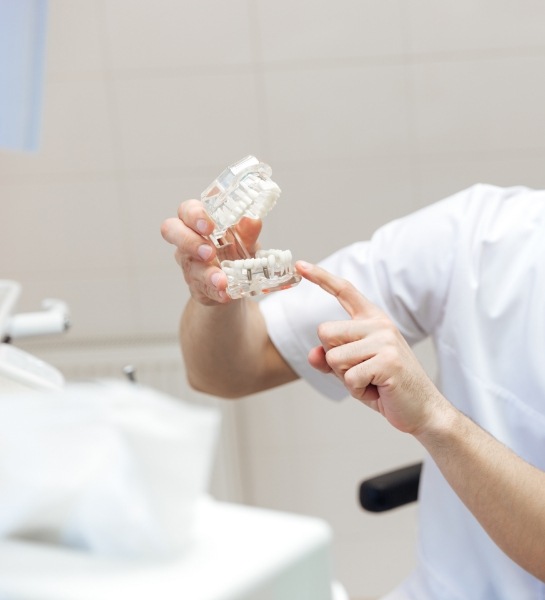 Dentist and patient looking at dental implant full-mouth reconstruction model