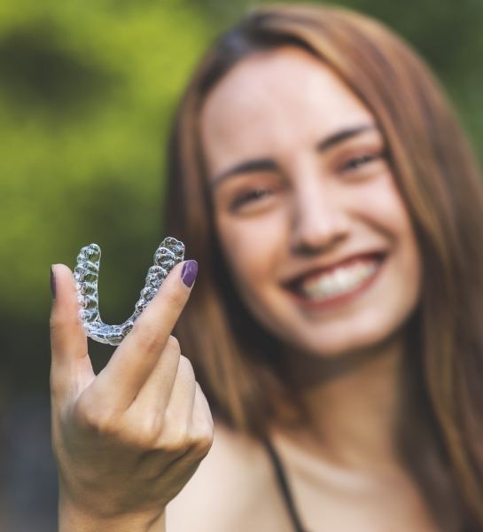 Woman holding up an Invisalign aligner 