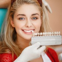 Woman's new porcelain veneers compared to shade chart after placement