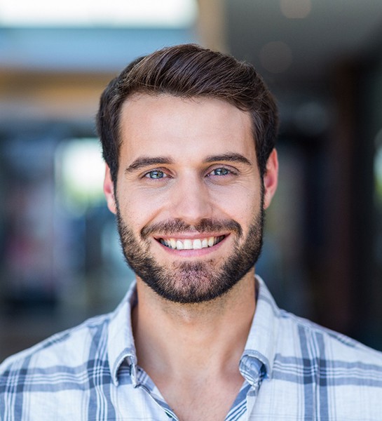 Man with beard and patterned shirt standing and smiling