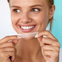 closeup of patient holding whitening strip 