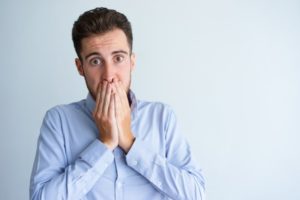 Embarrassed man covering mouth with bad breath needs his Naples dentist