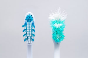 Clean, new toothbrush next to a frayed one that needs to be replaced