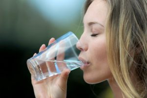 Healthy woman drinks water as recommended by her Naples dentist