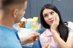 young woman with cracked teeth talking to her dentist 