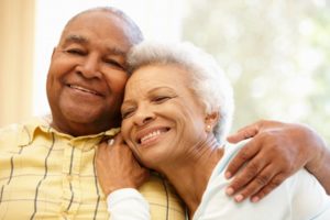 older couple smiling and hugging with dental implants