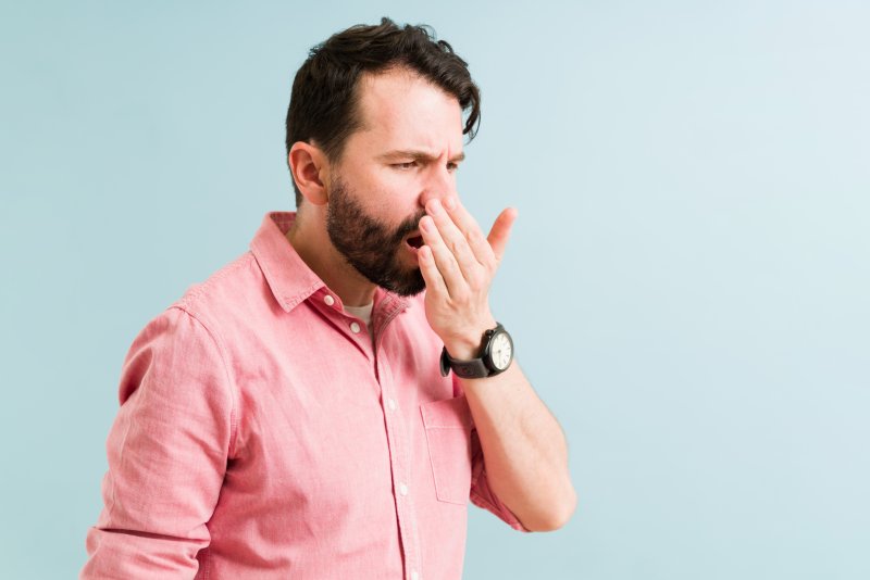 A man performing a smell test for bad breath with his hand