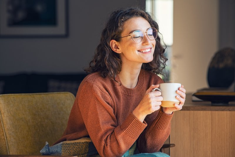 A woman smiling and drinking tea after her smile makeover