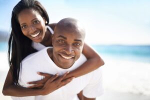 Man and woman in white shirts hugging at a beach